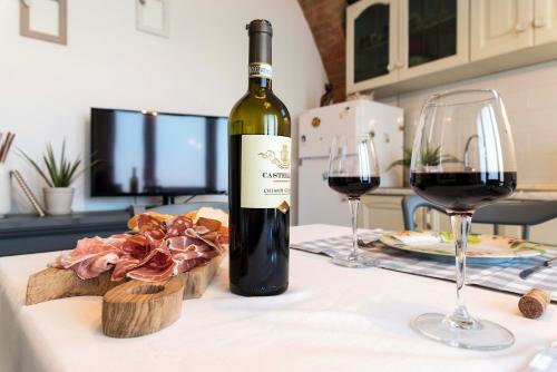 a bottle of wine sitting on a table with two glasses at Tosca's House in Palaia