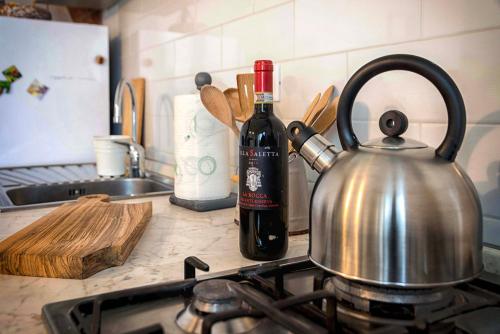 a tea kettle and a bottle of wine on a kitchen counter at Tosca's House in Palaia