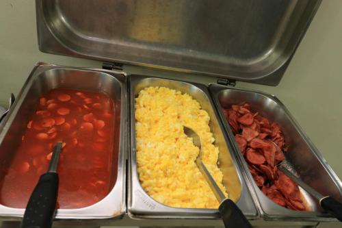 two metal trays of food with beans and tomatoes at Turis Hotel Centro in Campo Grande
