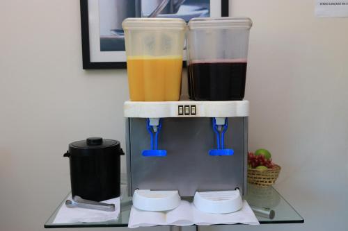 a coffee maker with three different types of drinks at Turis Hotel Centro in Campo Grande