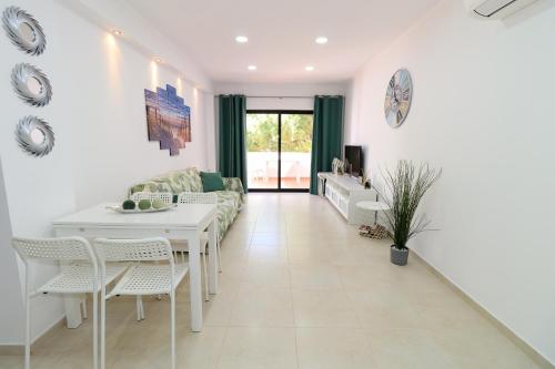 a living room with a couch and a table and chairs at Green paradise T2 apartment with pool top floor in Albufeira