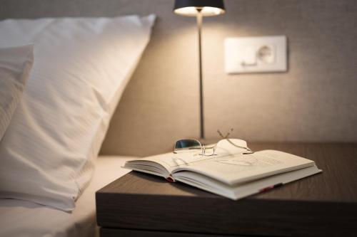 a book on a table next to a bed with a lamp at Hotel Florian&Godler in Karlovac