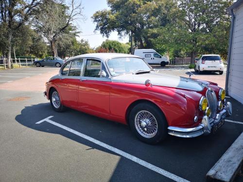 a red car parked in a parking lot at Hôtel Le Vert Bois in Dolus d'Oléron