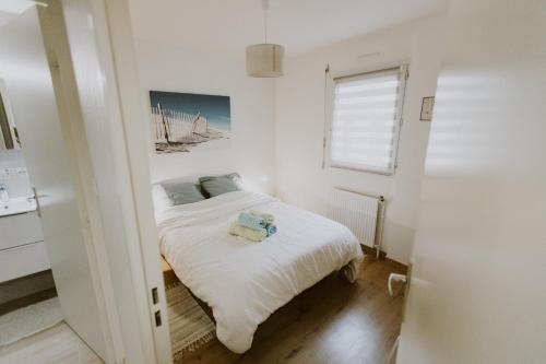 une chambre avec un lit avec des draps blancs et une fenêtre dans l'établissement Appartement 4 personnes jardin et parking, à Vannes