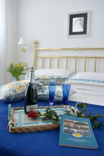 a bottle of wine and two glasses on a bed at La Kenzia Casa Vacanze in Maiori