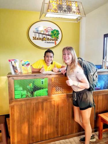 a woman and a boy standing at a counter at Mango House in Sukhothai