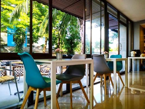 a dining room with chairs and a table and windows at Beerapan Hotel in Bangkok