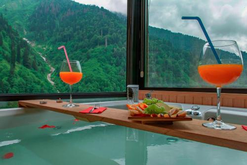 two glasses of orange juice sitting on a table next to a window at Ayder Villa de Pelit Hotel in Ayder Yaylasi