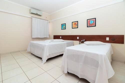 a room with two beds with white sheets at Turis Hotel Centro in Campo Grande