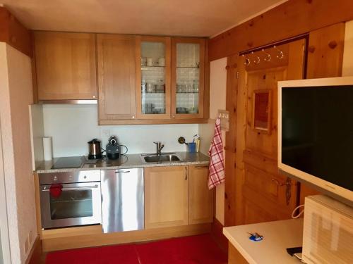 a small kitchen with wooden cabinets and a sink at Lovely Studio Bristol with swimming-pool Villars in Villars-sur-Ollon