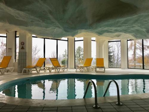 a swimming pool with yellow chairs and a large building at Lovely Studio Bristol with swimming-pool Villars in Villars-sur-Ollon