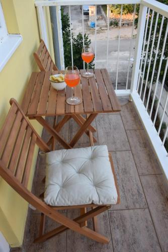 a wooden table with two wine glasses on a balcony at APP LU 5 in Novi Vinodolski