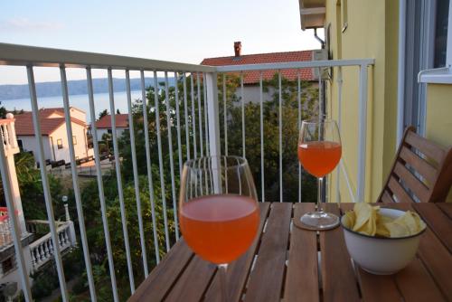 two glasses of wine sitting on a wooden table on a balcony at APP LU 5 in Novi Vinodolski