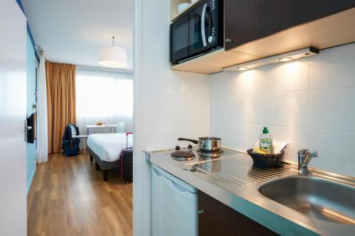 a kitchen with a sink and a counter top at Aparthotel Adagio Access Strasbourg Illkirch in Illkirch-Graffenstaden