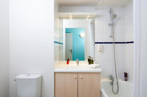 a bathroom with a sink and a toilet and a mirror at Aparthotel Adagio Access Strasbourg Illkirch in Illkirch-Graffenstaden