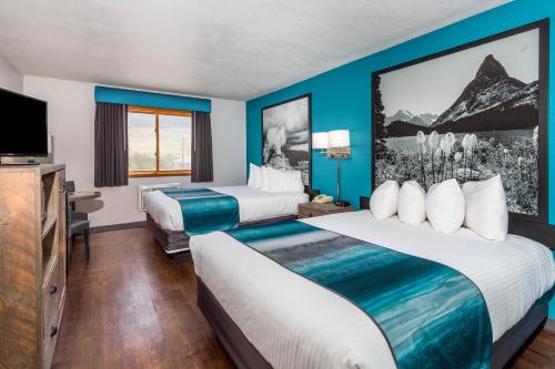 a hotel room with two beds and a flat screen tv at Super 8 by Wyndham Gardiner/Yellowstone Park Area in Gardiner