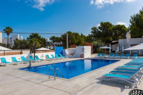 einen Pool mit blauen Liegestühlen und einem Pool in der Unterkunft Aparthotel Vibra Club Maritim in Bucht von San Antonio
