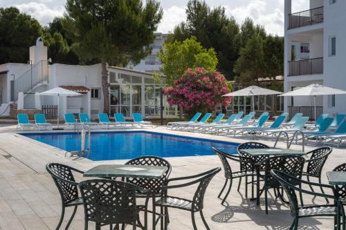 un gruppo di sedie e tavoli accanto alla piscina di Aparthotel Vibra Club Maritim a Baia di Sant'Antoni