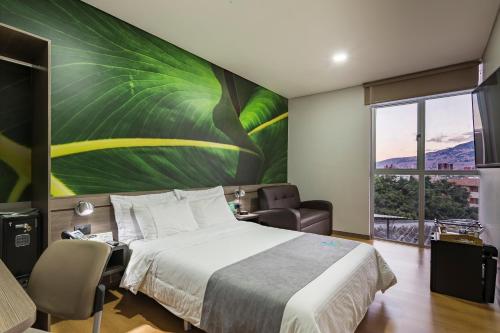 a bedroom with a large leaf mural on the wall at Hotel Vivre in Medellín