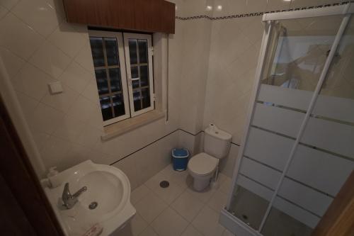 a bathroom with a toilet and a sink and a shower at Papôa Beach House in Peniche