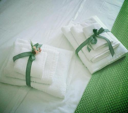 2 toallas blancas con arcos verdes en una cama en B&B Sabin Ross, en Margherita di Savoia