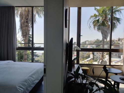 a bedroom with a bed and a view of a palm tree at Luxury Suites by Notaly Ariel in Haifa