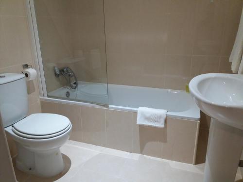 a white toilet sitting next to a bath tub in a bathroom at Hotel Riomar in Lagos