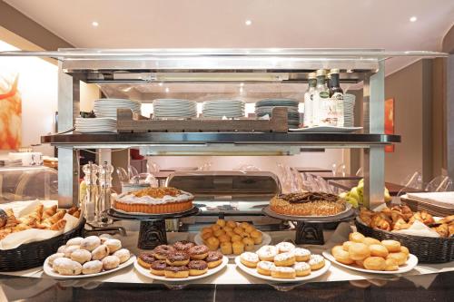 uma linha de buffet com muitos tipos diferentes de pastelarias em B&B Hotel Malpensa Lago Maggiore em Vergiate