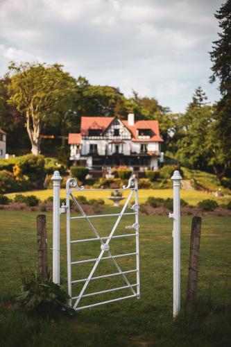 a white gate in front of a large house at Craig-y-Dderwen Riverside Hotel in Betws-y-coed