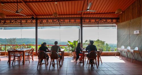 a group of people sitting at tables in a restaurant at The Estate Resort , Mangalore in Mūdbidri