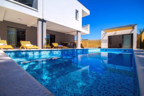 a swimming pool in front of a house at Villa Tela in Kučiće