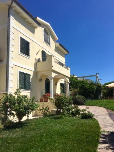 a white house with a balcony and green grass at Villa Luce B&B in Olbia