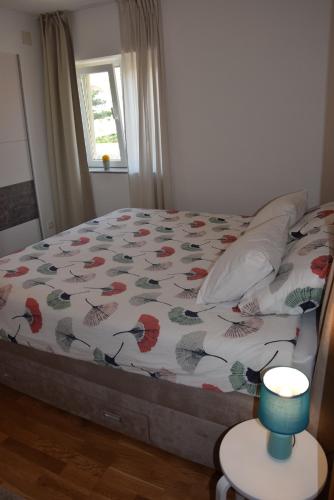 a bedroom with a bed with a comforter and a window at APP LU 5 in Novi Vinodolski