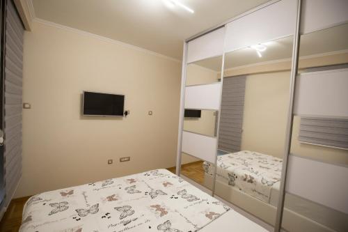 a bedroom with two beds and a tv on the wall at Apartman LUNA in Trebinje