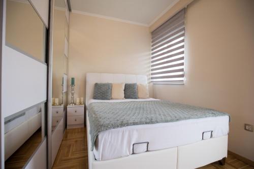 a white bedroom with a bed and a window at Apartman LUNA in Trebinje