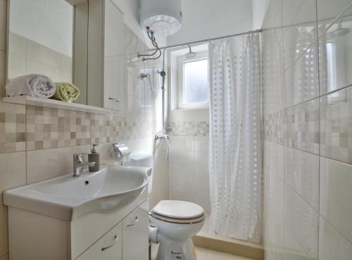 a white bathroom with a toilet and a sink at Apartment Fortica in Senj