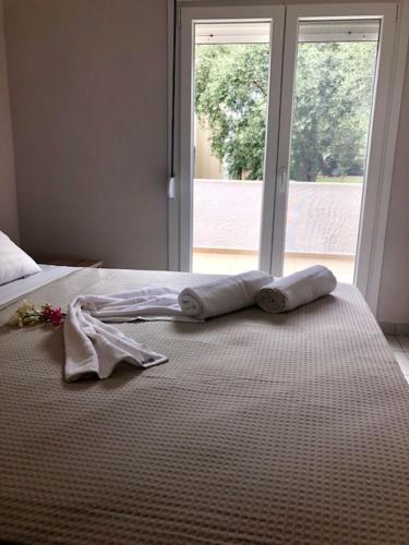 a bed with two towels on it with a window at Sofimel Apartment in Skala Sotiros