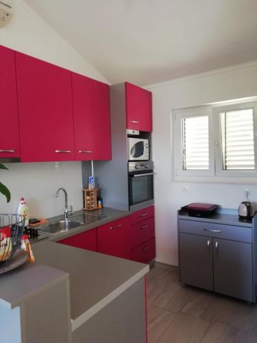 a kitchen with red cabinets and a sink at Apartments Hana in Goveđari