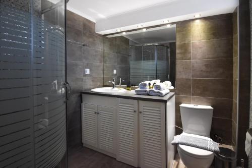 a bathroom with a sink and a toilet and a mirror at Hermes Hotel in Kissamos