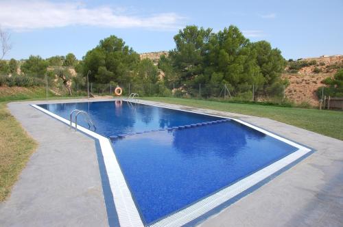 a swimming pool with blue water in a yard at Càmping Terra Alta in Bot