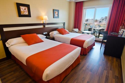 アルムニェーカルにあるBahía Almuñecarのベッド2台と窓が備わるホテルルームです。