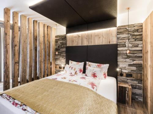 a bedroom with a large bed and wooden walls at Hotel Tyrol in Malles Venosta