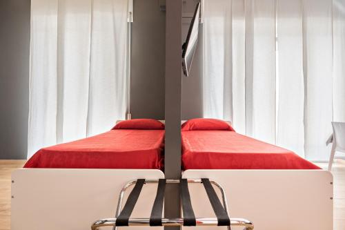 a bedroom with two beds with red sheets and a chair at Affittacamere My Home in La Spezia