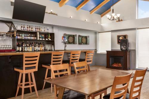 a bar with a wooden table and chairs and a fireplace at Days Inn & Suites by Wyndham Moncton in Moncton
