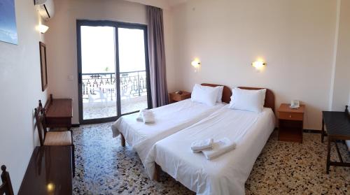 a bedroom with a large bed with white sheets and a window at Anetis Hotel in Tsilivi