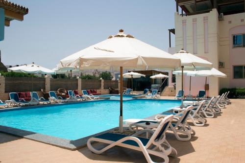 a swimming pool with chairs and umbrellas at 4S Hotel Dahab in Dahab