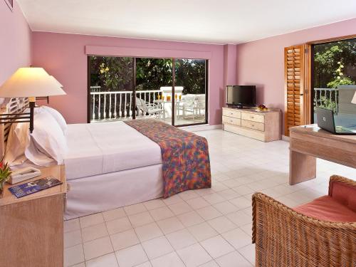 a bedroom with a bed and a television and a balcony at Hotel Tocarema in Girardot