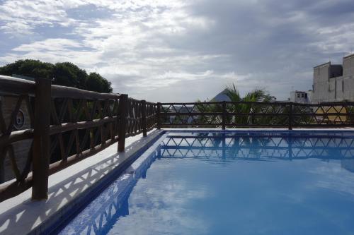 a swimming pool with a fence and blue water at Las Palmas Condominio in Playa del Carmen