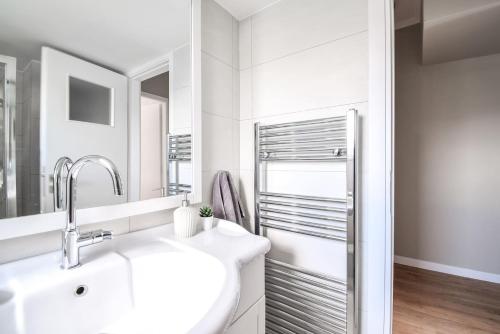 een witte badkamer met een wastafel en een spiegel bij Penthouse 3BD apt w/ sea-view in Athenian Riviera in Athene