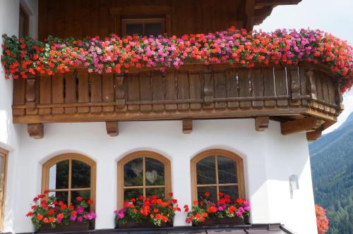 a building with a balcony with flowers on it at Pension Strolz in Sankt Anton am Arlberg